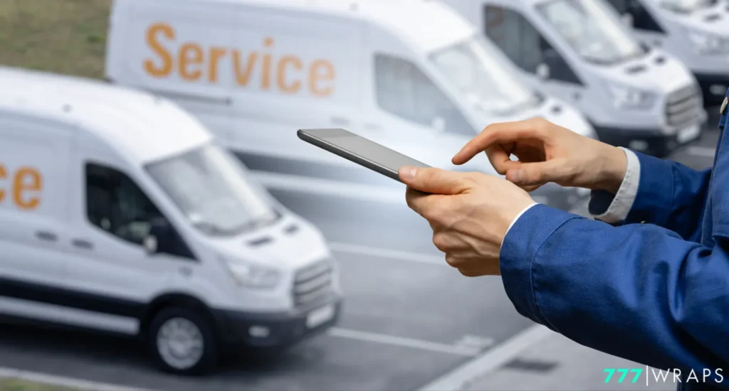 A man holds a smartphone in front of a fleet of branded vans, showcasing vehicle advertising potential in Amarillo, TX